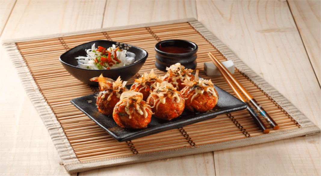 "Japanese street vendor preparing takoyaki balls with toppings like bonito flakes and mayo"