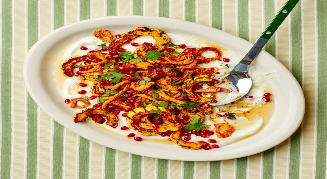 Roasted delicata squash slices topped with golden crispy onions on a serving plate