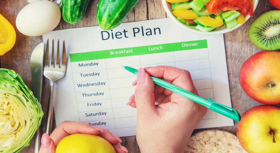Fresh vegetables, fruits, rice, eggs and clean water placed on a wooden table as part of a healthy diet plan