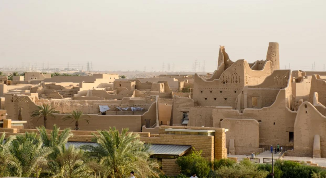 Saudi men performing the traditional Ardah sword dance with a backdrop of desert tents, symbolizing the culture and traditions of Saudi Arabia.