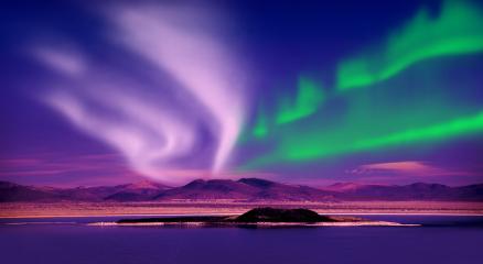 Northern lights over a snow-covered Icelandic glacier and mountains