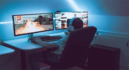 A gamer playing on a high-end setup with colorful lights