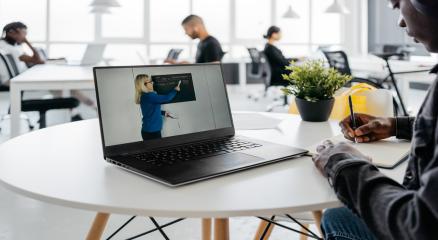 A student learning online using a laptop, surrounded by books and coffee, symbolizing affordable education.