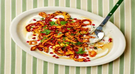 Roasted delicata squash slices topped with golden crispy onions on a serving plate