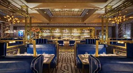 A luxurious London restaurant with blue velvet seating, golden accents, and a stylish bar interior.